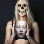 Junge Frau mit Maske und Totenschädel